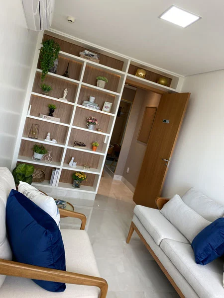 Sala de espera com estante decorativa e sofás claros